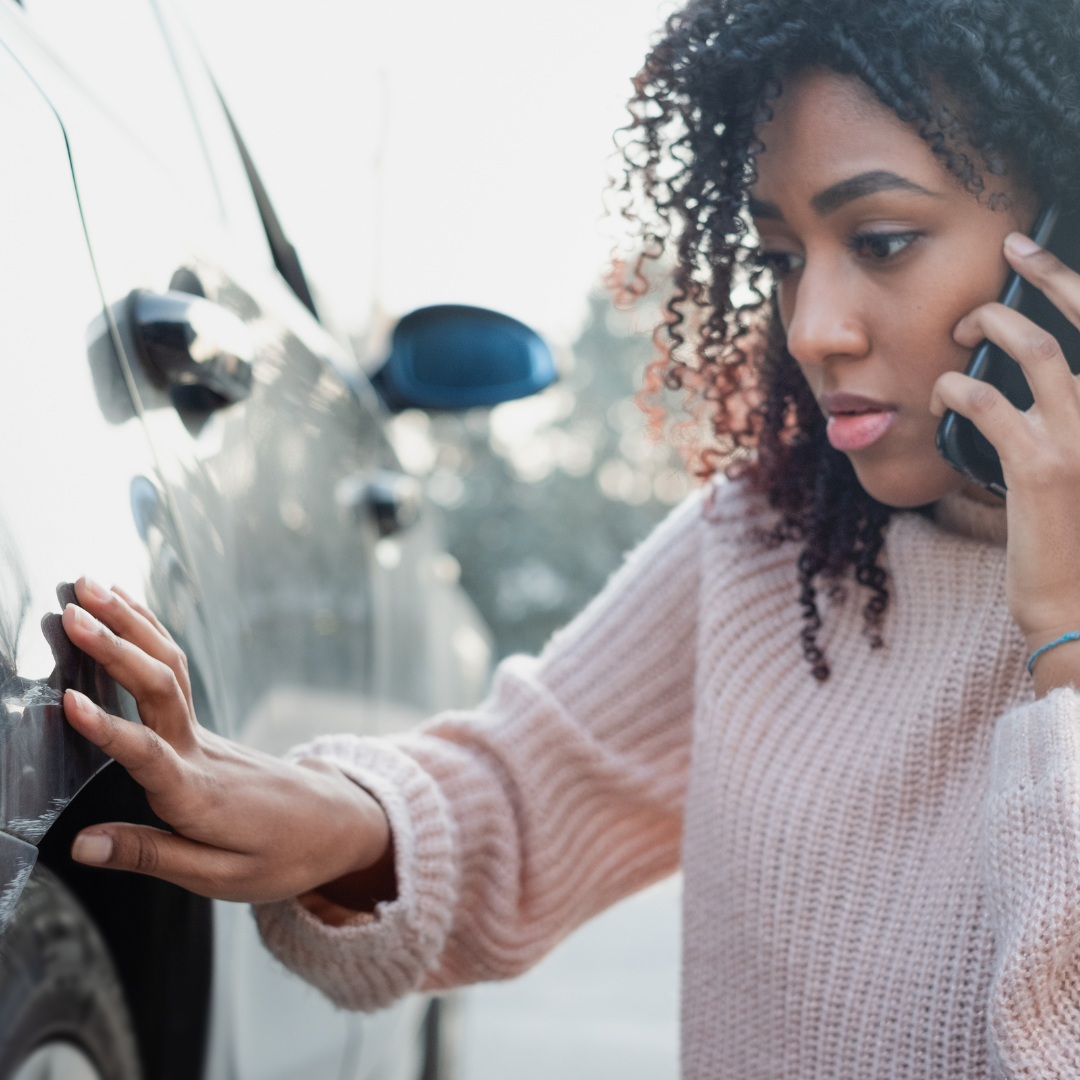 woman inspecting damage to car after an accident