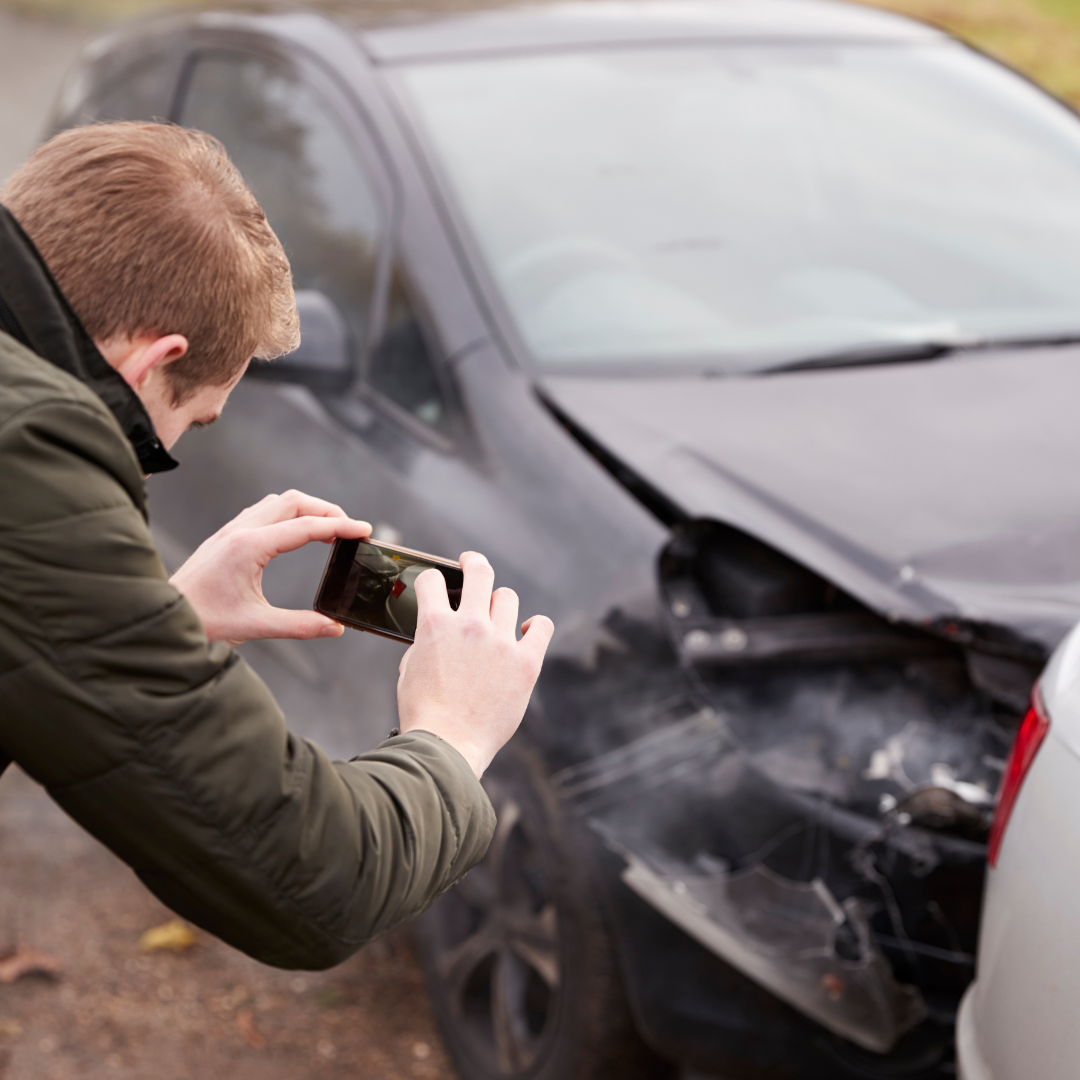 man taking pictures after car accident