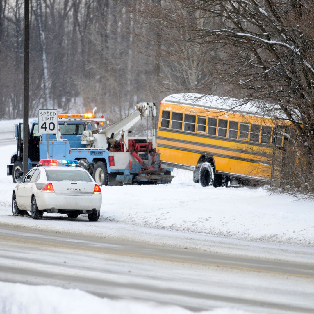 a bus in a ditch on a snowy day being towed 