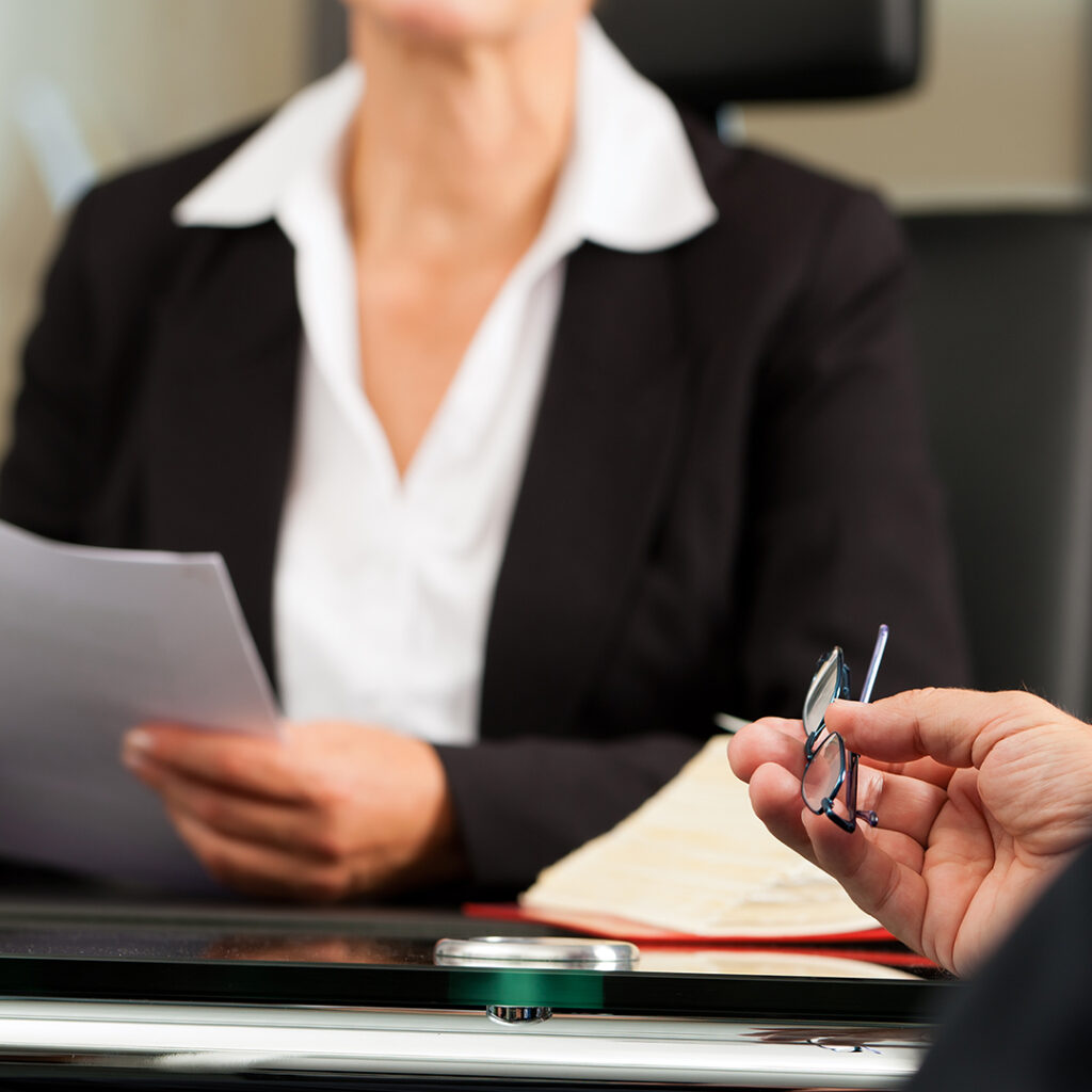 two people in suits across a desk from each other