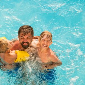 A dad swimming with his kids.