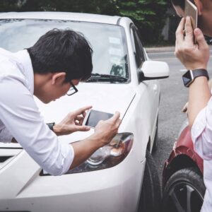  A man taking photos of car accident damage.