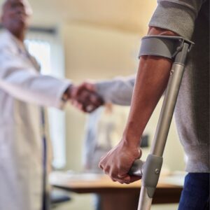 man with a crutch shaking hands with a doctor