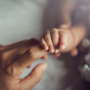 newborn holding on to its father's finger
