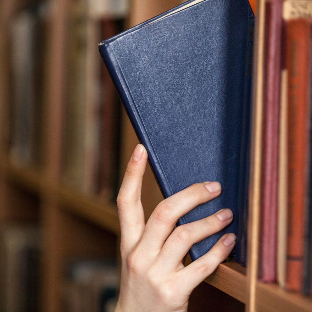 photo of person putting book on shelf