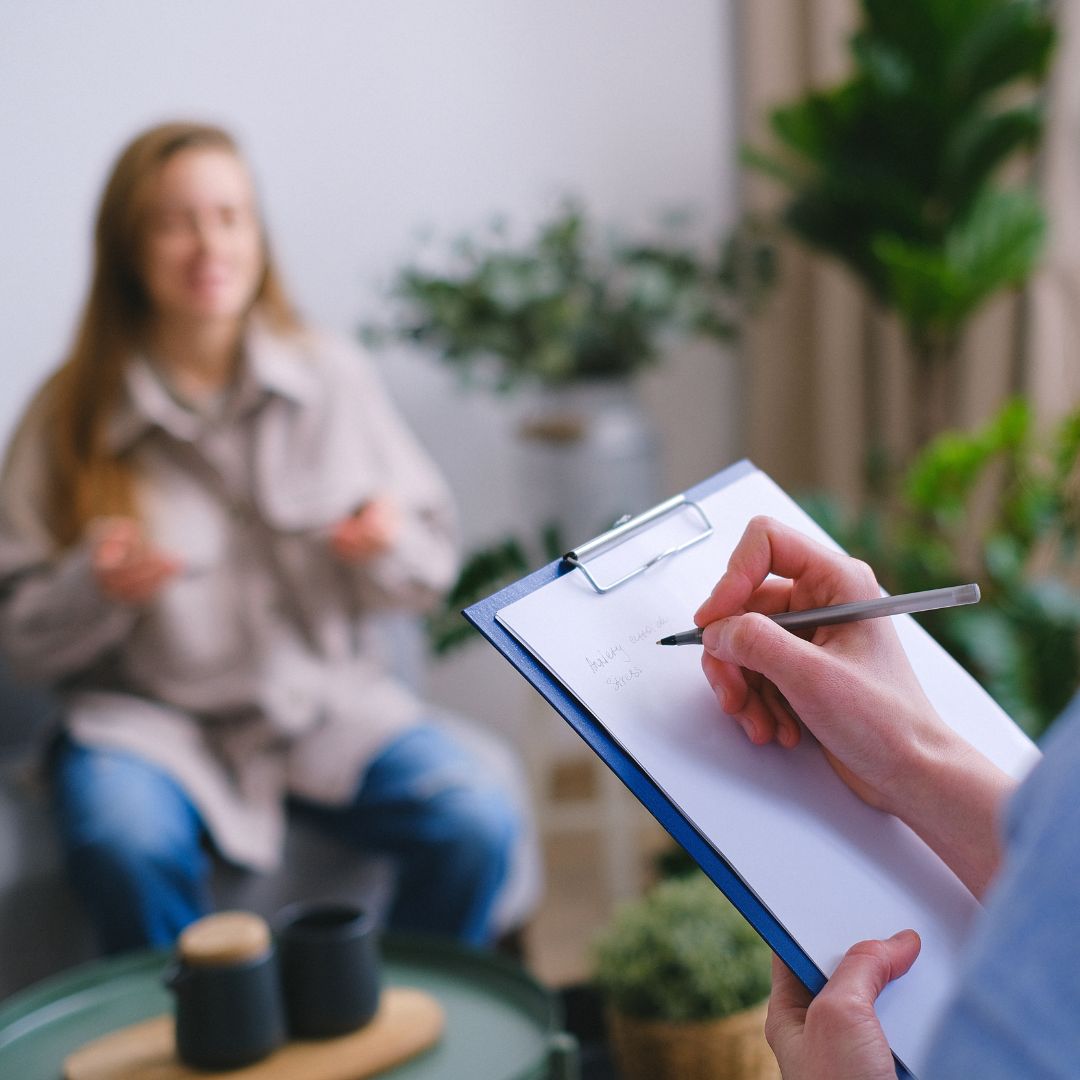 A person taking notes while speaking to another person