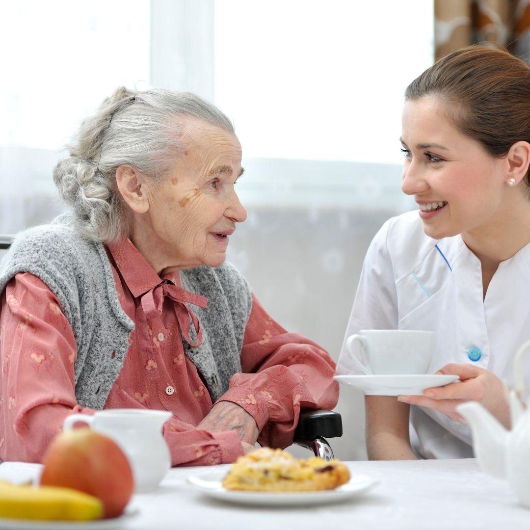 nurse talking to elderly woman in nursing home