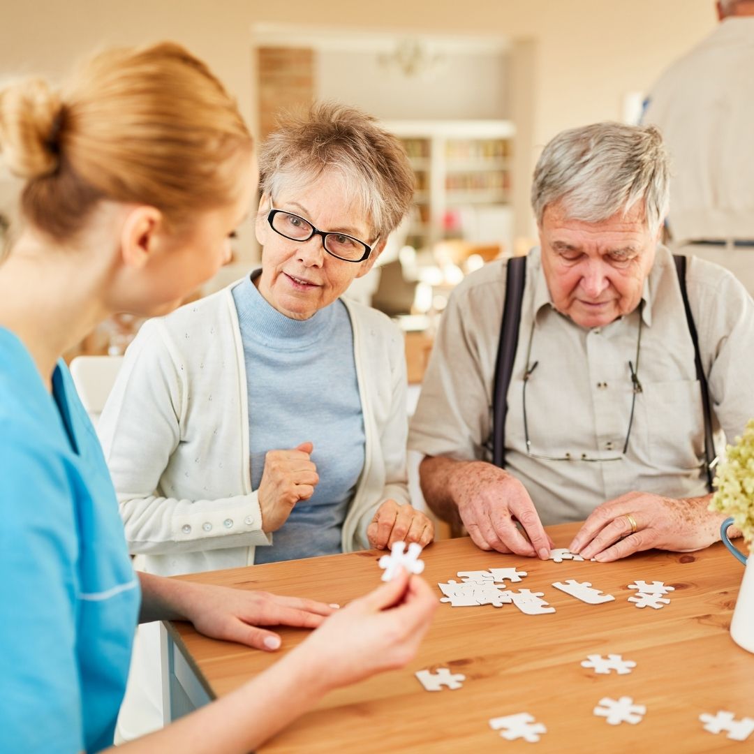 nurse talking to elderly couple in nursing home