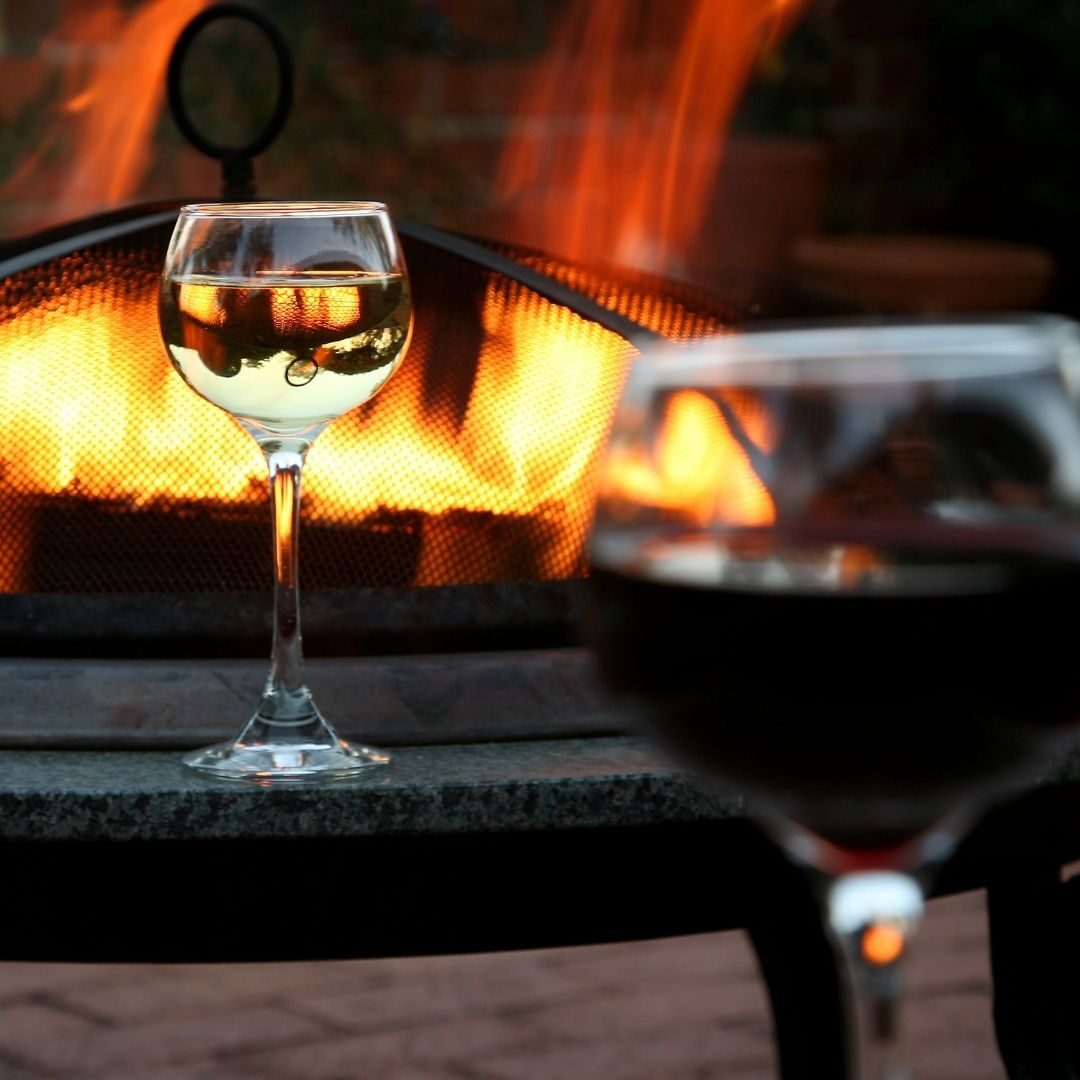 Two glasses of wine by a fire pit