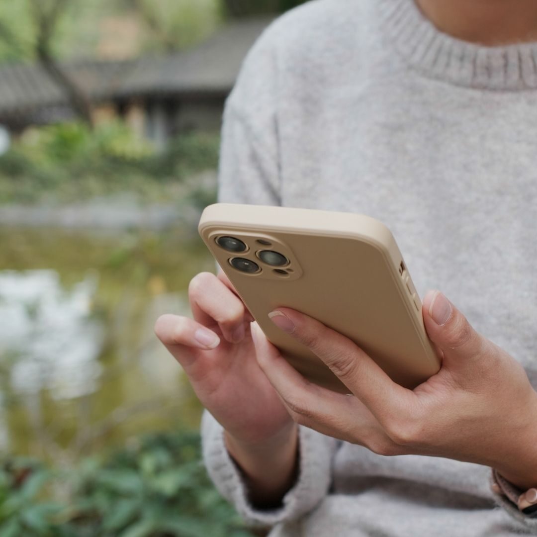 A woman holding a phone while in their backyard